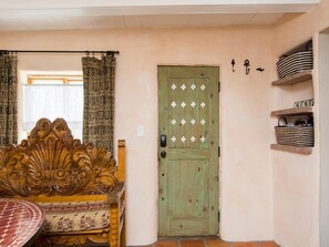A room with a wooden door, a bench, and shelves with baskets.