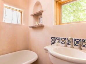 Un bagno con due lavandini, una finestra e uno schienale piastrellato.
