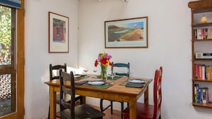 Un comedor con una mesa de madera, sillas, un jarrón con flores y cuadros en la pared.