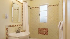 Ein Badezimmer mit Waschbecken, Spiegel und Duschbereich.