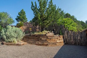 A landscaped garden with a wooden retaining wall, various shrubs, and trees.