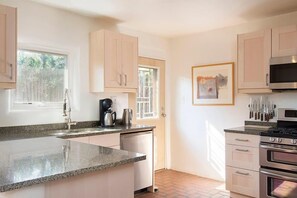 A kitchen with a granite countertop, stainless steel appliances, and light-colored cabinetry.