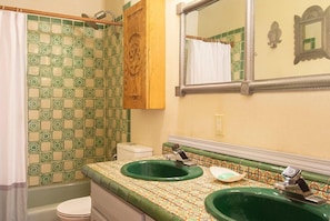 Un bagno con due lavandini verdi, un water e una tenda per la doccia.