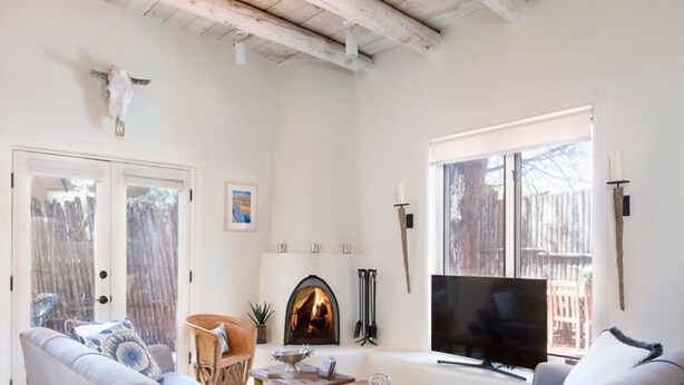 Sala de estar com lareira, sofá, TV e vista para o exterior.