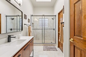 Un bagno moderno con doccia vetrata, mobile bagno in legno e un ampio specchio.