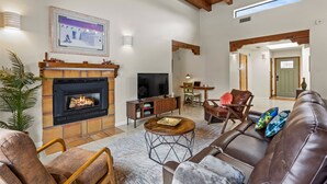 Una sala de estar con chimenea, sofá de cuero y televisor.