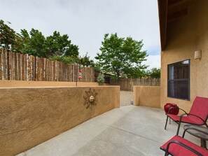 A patio area with a concrete floor, a wooden fence, and a red chair.