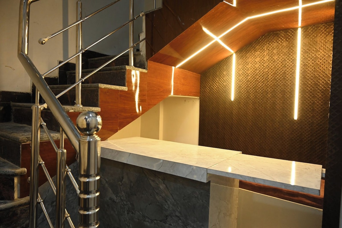 A modern interior with a marble staircase, a reception desk, and a textured wall with geometric lighting.