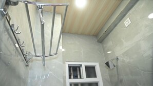 Un baño moderno con cabina de ducha de vidrio, ventana y perchero.