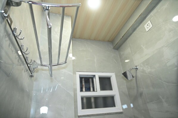A modern bathroom with a glass shower enclosure, a window, and a towel rack. - Hotel Royal Radiant (Ranchi)