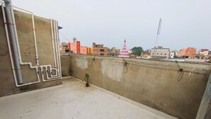 Terraza en la azotea con suelo de hormigón, una planta en maceta y tuberías visibles.