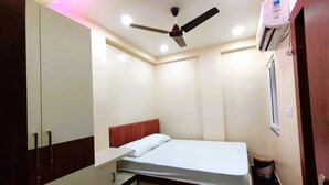 Un dormitorio pequeño con cama, ventilador de techo, iluminación empotrada y aire acondicionado.
