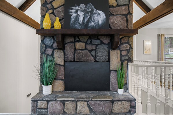 A stone fireplace with a black screen, two potted plants, and yellow vases on a shelf. - Lake View Newly Renovated (Birmingham)