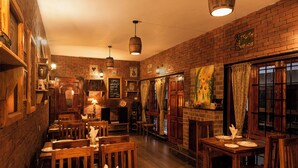 Een gezellig restaurant met bakstenen muren, houten tafels en hangende lampen.