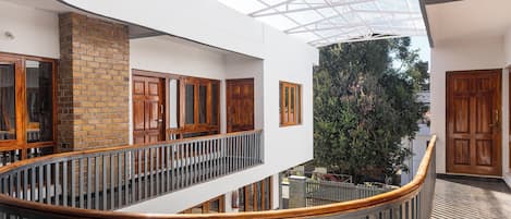 A multi-level interior with a glass ceiling, wooden doors, and a brick wall.