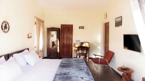 Een hotelkamer met een bed, een bureau, een stoel, een televisie en een deur.