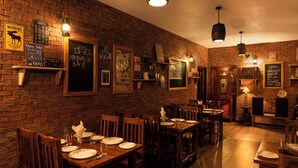 Een gezellig restaurant met bakstenen muren, houten tafels, diverse borden en decoraties.