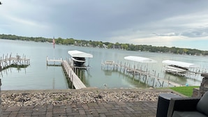 A lakeside patio with a dock, outdoor seating, and a view of the water.