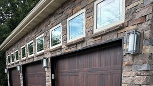 A stone building with two garage doors and potted ferns in front.