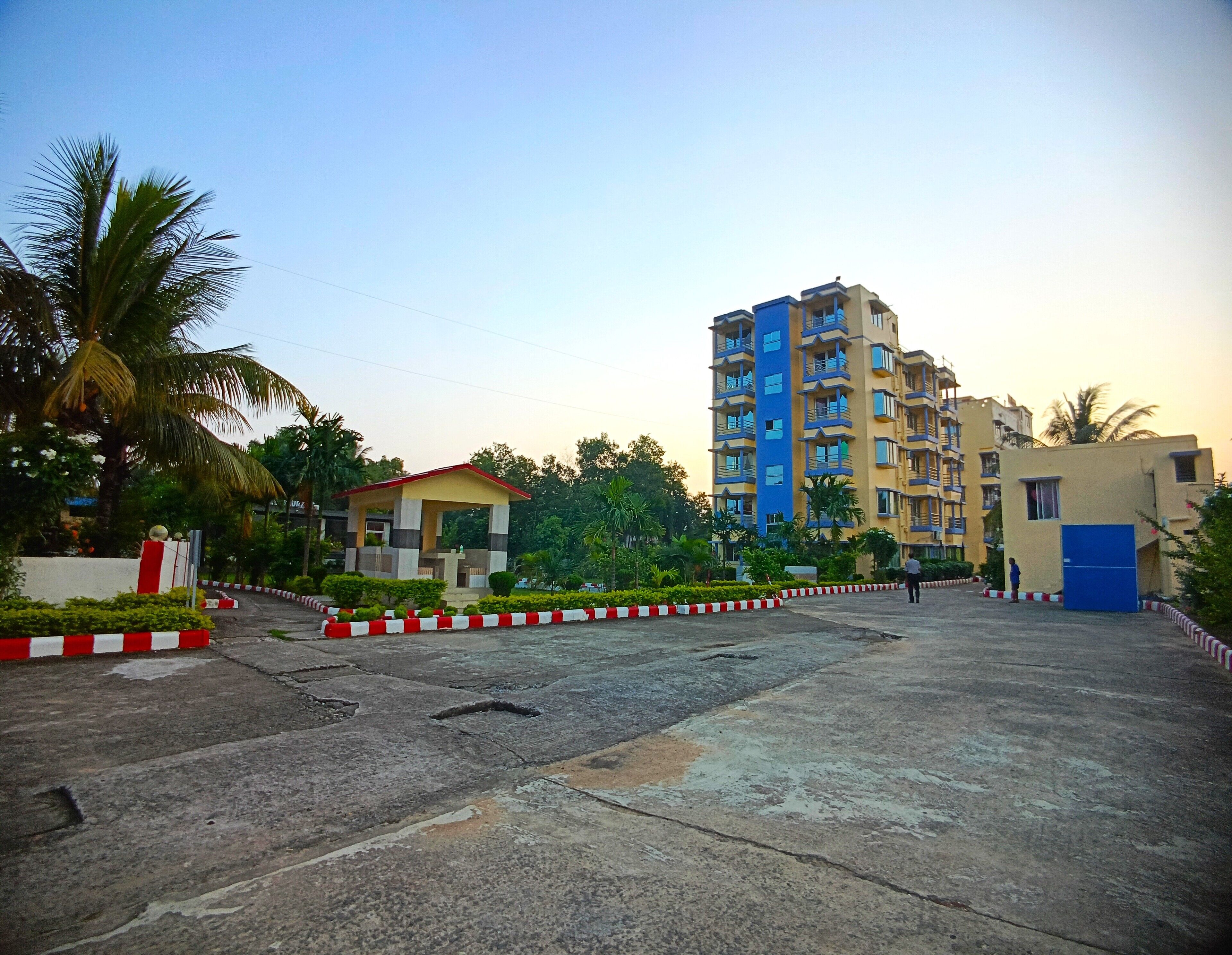 A multi-story residential building with balconies, a small pavilion, and a blue door.