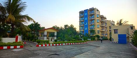 A multi-story residential building with balconies, a small pavilion, and a blue door.