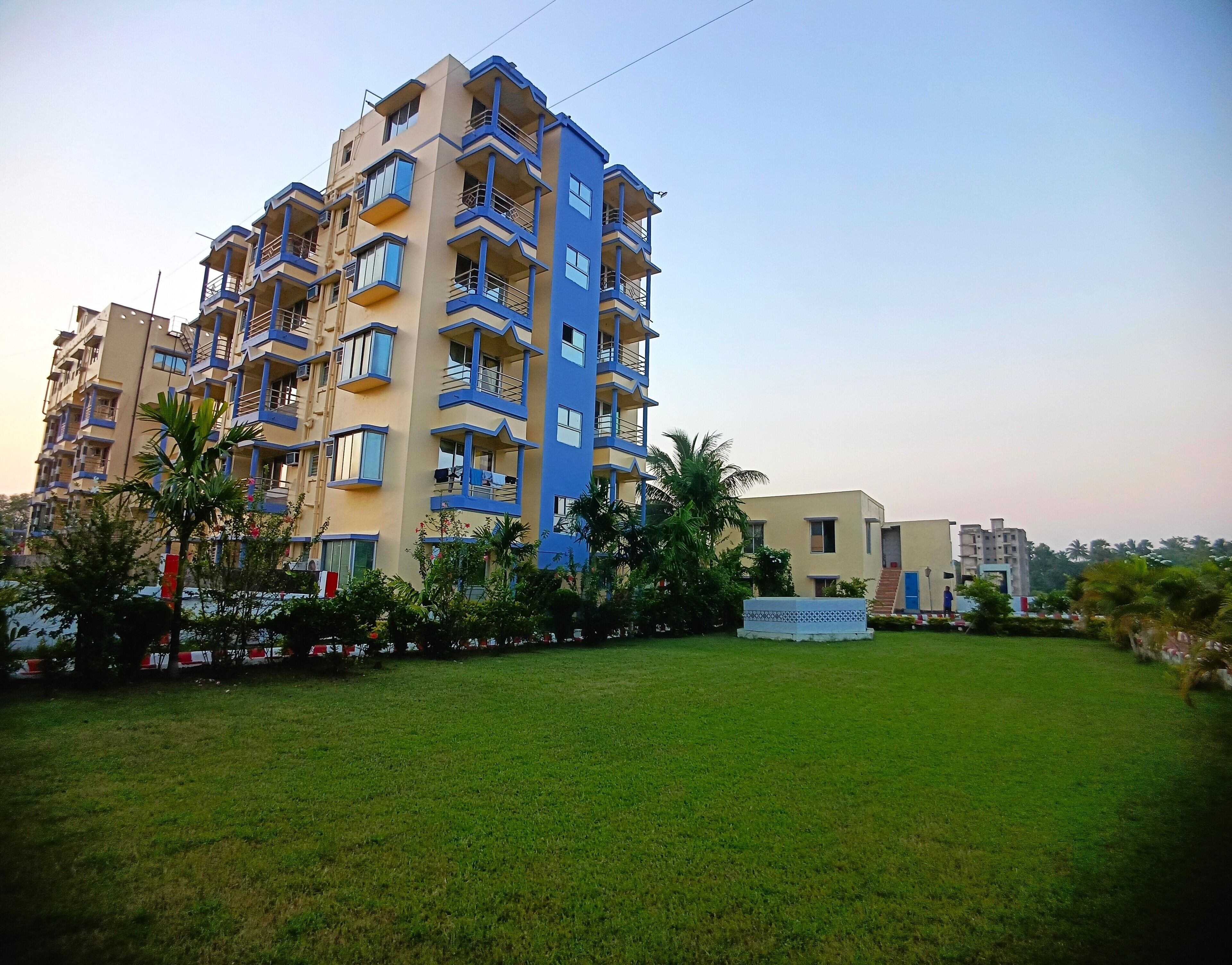 A multi-story residential building with balconies and a grassy courtyard.