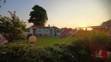 Un parque infantil con un tobogán y un árbol grande al fondo.