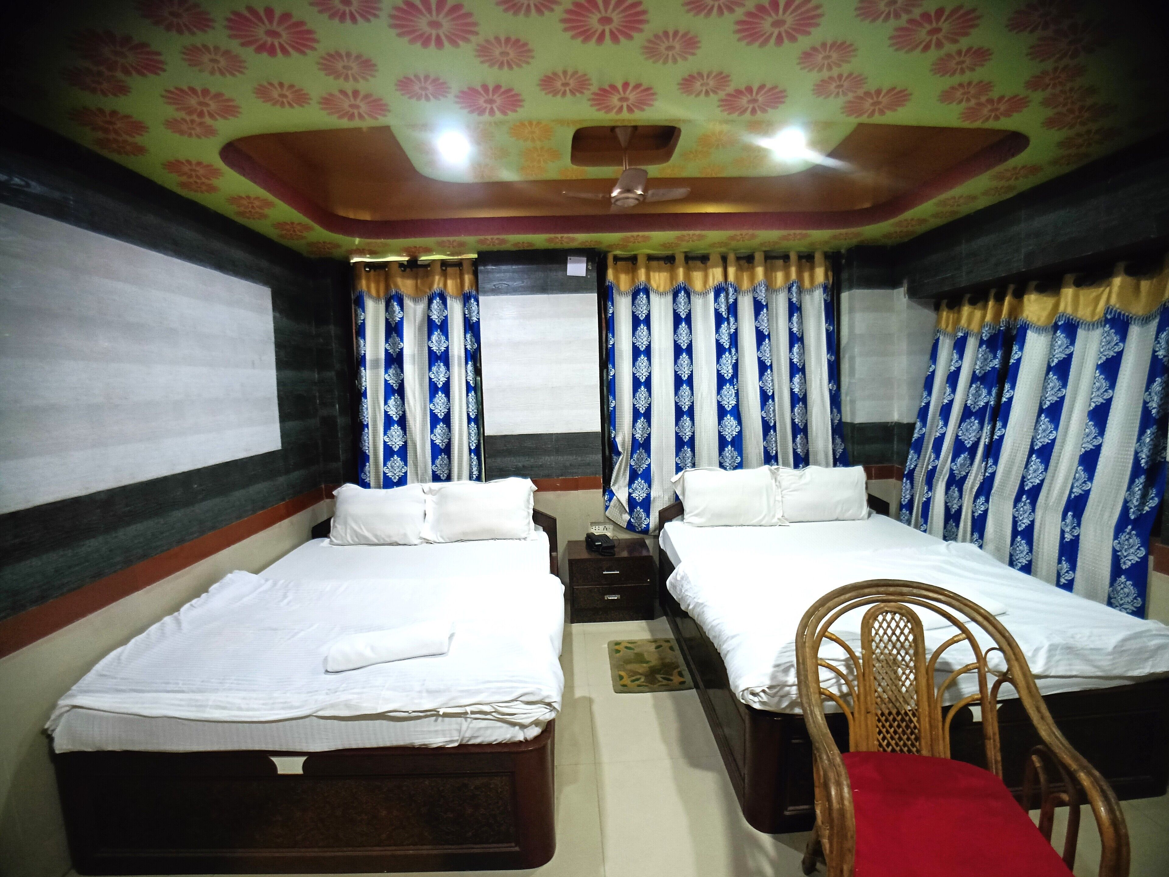 A room with two beds, a wooden chair, and a ceiling fan.