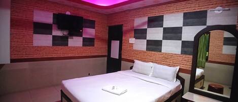 A bedroom with a bed, a ceiling fan, a mirror, and a checkered wall design.