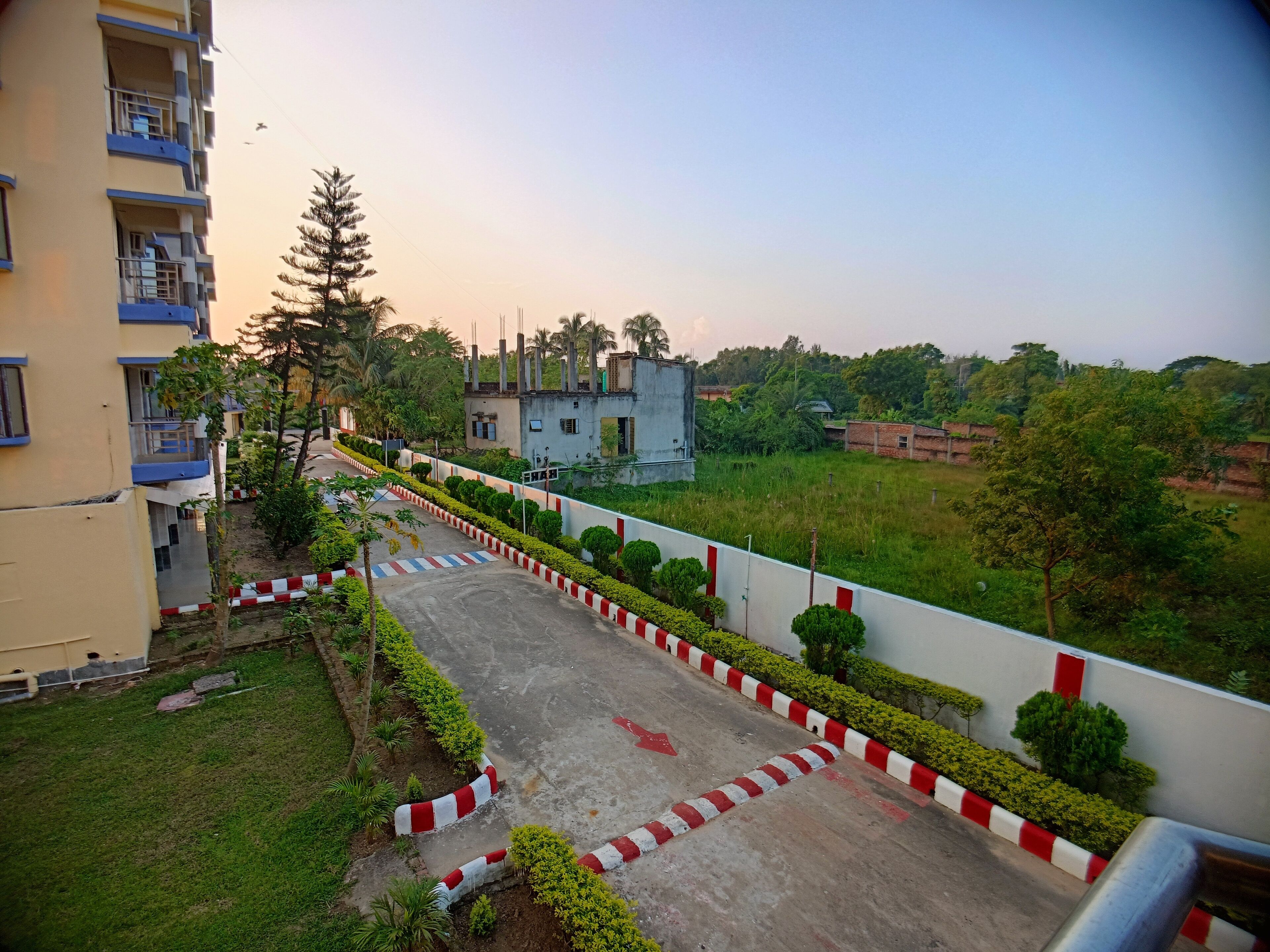 A residential area with a paved pathway, red and white curbs, and greenery.