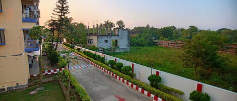 A residential area with a paved pathway, red and white curbs, and greenery.