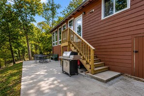A wooden cabin with a covered patio, a grill, and a dining area with outdoor furniture. - Hickory Haven • Cozy Lakefront Escape + Dock (cadiz)