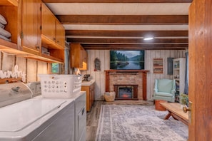 Un salon chaleureux avec une cheminée, un téléviseur et une vue sur une forêt.