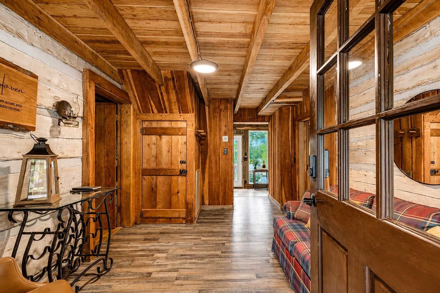 A wooden interior hallway with a bench, a door, and a lantern.