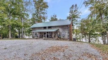 Situated in a natural setting, this cabin offers a welcoming entrance with a porch and outdoor seating.