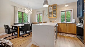 A modern kitchen with wooden cabinets, a large island, and a dining area with a table and chairs.