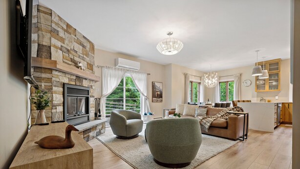 A modern living room with a stone fireplace, two armchairs, a sofa, and a wooden coffee table.