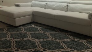 Un canapé d’angle blanc avec un tapis à motifs.