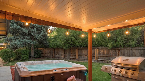 Ein Garten mit Whirlpool, Grill und Lichterketten.
