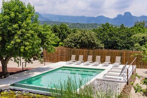 A rectangular pool with a tiled edge, surrounded by a wooden fence, with lounge chairs and a tree in the foreground. - Xolatlaco Tepoztlan Hotel Boutique (Tepoztlán)