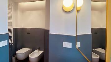Une salle de bain moderne avec un lavabo blanc, deux urinoirs et un bidet.