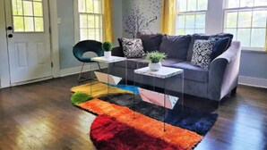 Una sala de estar con un sofá gris, una mesa de centro y un tapete colorido.