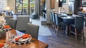 Ett modernt hotellrum med en matplats, ett kök och en balkong med utsikt över omgivningarna.