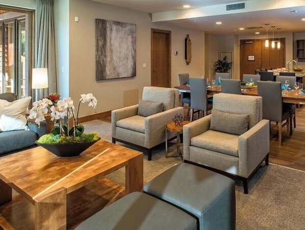 A hotel lobby with seating areas, a dining area, and a large abstract painting on the wall.
