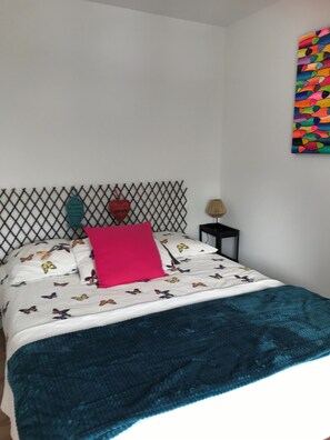 Cozy retreat with a diamond-patterned headboard, colorful bedding, and a vibrant abstract art piece.