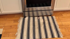 Una cocina con estufa, horno de acero inoxidable y ventana con vistas al exterior.