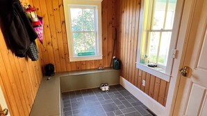 Una habitación con paredes de madera, una ventana, un banco y una puerta.