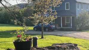 Una casa con entrada para coches, un automóvil estacionado y un jardín.