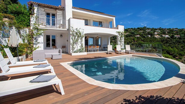 Une maison à deux étages dotée d’une piscine, d’un espace extérieur aménagé et offrant une vue sur les collines environnantes.
