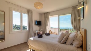 Une chambre avec un grand lit, une télévision et une vue sur la mer.